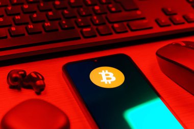 Prag, Çek Cumhuriyeti - 08 12 2025: Bitcoin logosunu gösteren klavyesi ve cep telefonu olan bir masanın yan görüntüsü. Bitcoin merkezi olmayan işlemler için dijital bir kripto para birimidir.