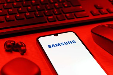 Prag, Çek Cumhuriyeti - 08 12 2025: Samsung logosunu gösteren klavyesi ve cep telefonu olan bir masanın yan görüntüsü. Samsung elektronik ve cihaz üreten bir teknoloji şirketi..