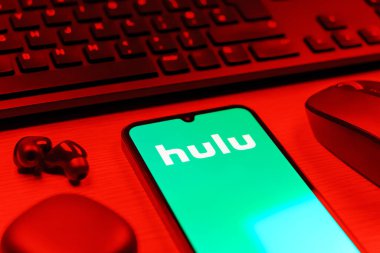 Prag, Çek Cumhuriyeti - 08 12 2025: Hulu logosunu gösteren klavyesi ve cep telefonu olan bir masanın yan görüntüsü. Hulu TV şovları, filmler ve canlı TV için bir yayın platformu..