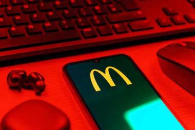 Prag, Çek Cumhuriyeti - 08 12 2025: McDonalds logosunu gösteren klavyesi ve cep telefonu olan bir masanın yan görüntüsü. McDonalds hamburger, patates kızartması ve daha fazlası sunan bir fast-food zinciri..