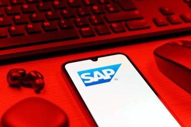 Prag, Çek Cumhuriyeti - 08 12 2025: SAP logosunu gösteren klavyesi ve cep telefonu olan bir masanın yan görüntüsü. SAP, şirket uygulamaları ve çözümleri sağlayan bir yazılım şirketidir..