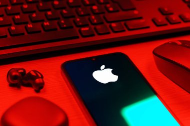 Prag, Çek Cumhuriyeti - 08 12 2025: Apple logosunu gösteren klavyesi ve cep telefonu olan bir masanın yan görüntüsü. Apple iPhone, bilgisayar ve hizmet üreten bir teknoloji şirketidir..