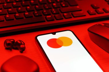 Prag, Çek Cumhuriyeti - 08 12 2025: Mastercard logosunu gösteren klavyesi ve cep telefonu olan bir masanın yan görüntüsü. Mastercard ödeme kartları ve hizmetler sağlayan bir finans şirketidir..