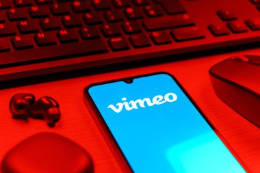 Prag, Çek Cumhuriyeti - 08 12 2025: Vimeo logosunu gösteren klavyesi ve cep telefonu olan bir masanın yan görüntüsü. Vimeo, yüksek kaliteli video sunucu ve paylaşımı için bir platformdur.