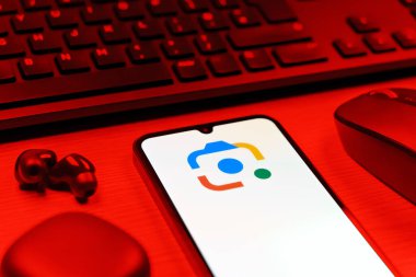Prag, Çek Cumhuriyeti - 08 12 2025: Google Lens logosunu gösteren klavyesi ve cep telefonu olan bir masanın yan görüntüsü. Google Lens, resimlerdeki görsel arama ve bilgi için kullanılan bir araçtır..