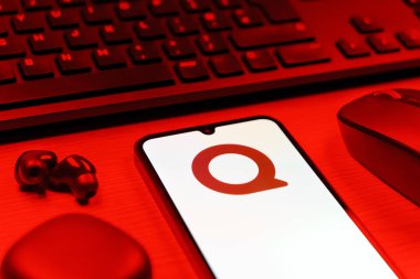 Prag, Çek Cumhuriyeti - 08 12 2025: Quora logosunu gösteren klavyesi ve cep telefonu olan bir masanın yan görüntüsü. Quora soru sormak ve bilgi paylaşmak için bir platformdur..