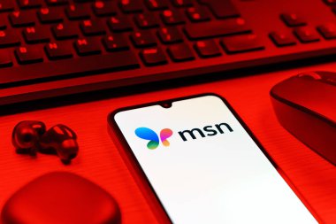 Prag, Çek Cumhuriyeti - 08 12 2025: MSN logosunu gösteren klavyesi ve cep telefonu olan bir masanın yan görüntüsü. MSN haber, e-posta ve çevrimiçi hizmetler için bir platformdur.