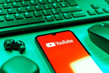 Prague, Czechia - 08 12 2025: A side view of a desk with a keyboard and a mobile phone displaying the Youtube logo. Youtube is a platform to watch and share videos worldwide.