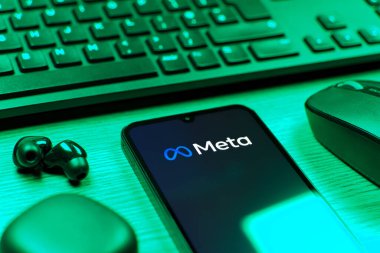 Prague, Czechia - 08 12 2025: A side view of a desk with a keyboard and a mobile phone displaying the Meta logo. Meta is a company offering social platforms like Facebook and Instagram.