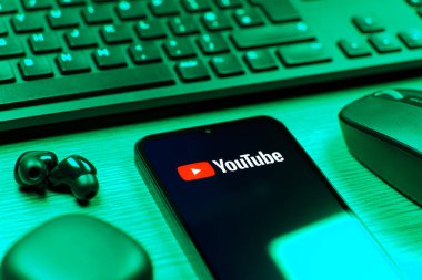 Prague, Czechia - 08 12 2025: A side view of a desk with a keyboard and a mobile phone displaying the Youtube logo. Youtube is a platform to watch and share videos worldwide.