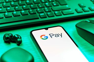Prague, Czechia - 08 12 2025: A side view of a desk with a keyboard and a mobile phone displaying the Google Pay logo. Google Pay is a platform for easy and secure digital payments.