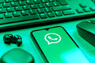 Prague, Czechia - 08 12 2025: A side view of a desk with a keyboard and a mobile phone displaying the WhatsApp logo. WhatsApp is an app for sending texts, calls, and media.