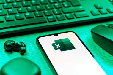Prague, Czechia - 08 12 2025: A side view of a desk with a keyboard and a mobile phone displaying the Excel logo. Excel is a software for spreadsheets, data analysis, and calculations.