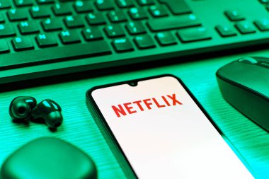 Prague, Czechia - 08 12 2025: A side view of a desk with a keyboard and a mobile phone displaying the Netflix logo. Netflix is a streaming platform for movies and TV shows.