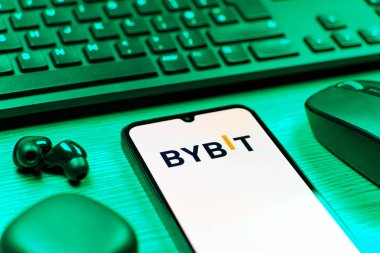 Prague, Czechia - 08 12 2025: A side view of a desk with a keyboard and a mobile phone displaying the Bybit logo. Bybit is a platform for trading cryptocurrencies and derivatives.