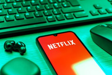 Prague, Czechia - 08 12 2025: A side view of a desk with a keyboard and a mobile phone displaying the Netflix logo. Netflix is a streaming platform for movies and TV shows.