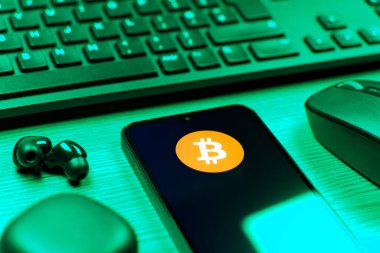 Prag, Çek Cumhuriyeti - 08 12 2025: Bitcoin logosunu gösteren klavyesi ve cep telefonu olan bir masanın yan görüntüsü. Bitcoin merkezi olmayan işlemler için dijital bir kripto para birimidir.