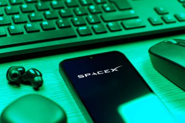 Prag, Çek Cumhuriyeti - 08 12 2025: SpaceX logosunu gösteren klavyesi ve cep telefonu olan bir masanın yan görüntüsü. SpaceX uzay keşfi ve roket fırlatmaları için özel bir şirkettir..