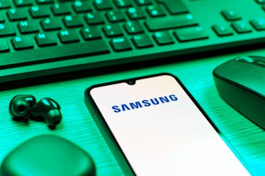Prag, Çek Cumhuriyeti - 08 12 2025: Samsung logosunu gösteren klavyesi ve cep telefonu olan bir masanın yan görüntüsü. Samsung elektronik ve cihaz üreten bir teknoloji şirketi..