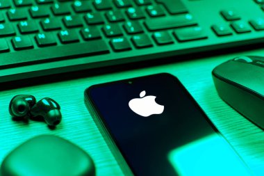 Prag, Çek Cumhuriyeti - 08 12 2025: Apple logosunu gösteren klavyesi ve cep telefonu olan bir masanın yan görüntüsü. Apple iPhone, bilgisayar ve hizmet üreten bir teknoloji şirketidir..
