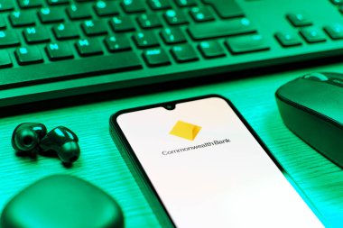 Prag, Çek Cumhuriyeti - 08 12 2025: Commonwealth Bank logosunu gösteren klavyesi ve cep telefonu olan bir masanın yan görüntüsü. Commonwealth Bank, Avustralya 'da finansal hizmetler sağlayan bir bankadır..