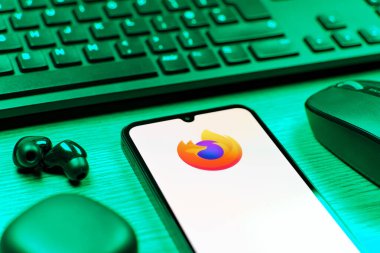 Prag, Çek Cumhuriyeti - 08 12 2025: Firefox logosunu gösteren klavyesi ve cep telefonu olan bir masanın yan görüntüsü. Firefox hızlı ve güvenli internet taraması için bir web tarayıcısıdır.