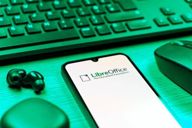 Prag, Çek Cumhuriyeti - 08 12 2025: LibreOffice logosunu gösteren klavyesi ve cep telefonu olan bir masanın yan görüntüsü. LibreOffice, dokümanlar, hesap tabloları ve sunumlar oluşturmak için özgür bir yazılım takımıdır..