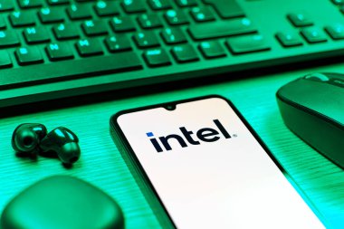 Prag, Çek Cumhuriyeti - 08 12 2025: Intel logosunu gösteren klavyesi ve cep telefonu olan bir masanın yan görüntüsü. Intel işlemci ve bilgisayar donanımı üreten bir teknoloji şirketidir..