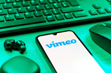 Prag, Çek Cumhuriyeti - 08 12 2025: Vimeo logosunu gösteren klavyesi ve cep telefonu olan bir masanın yan görüntüsü. Vimeo, yüksek kaliteli video sunucu ve paylaşımı için bir platformdur.