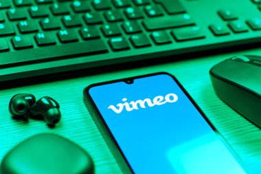 Prag, Çek Cumhuriyeti - 08 12 2025: Vimeo logosunu gösteren klavyesi ve cep telefonu olan bir masanın yan görüntüsü. Vimeo, yüksek kaliteli video sunucu ve paylaşımı için bir platformdur.