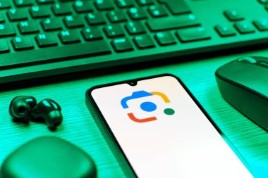 Prag, Çek Cumhuriyeti - 08 12 2025: Google Lens logosunu gösteren klavyesi ve cep telefonu olan bir masanın yan görüntüsü. Google Lens, resimlerdeki görsel arama ve bilgi için kullanılan bir araçtır..