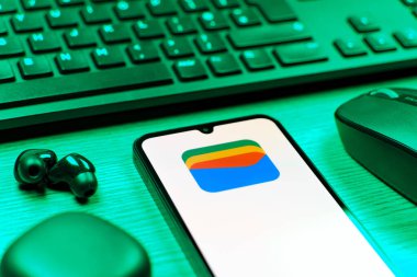 Prag, Çek Cumhuriyeti - 08 12 2025: Google Cüzdan logosunu gösteren klavyesi ve cep telefonu olan bir masanın yan görüntüsü. Google Cüzdanı dijital ödeme yöntemlerini depolamak ve kullanmak için bir platformdur.