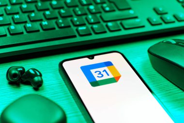 Prag, Çek Cumhuriyeti - 08 12 2025: Google Takvim logosunu gösteren klavyesi ve cep telefonu olan bir masanın yan görüntüsü. Google Takvimi olayları zamanlamak ve yönetmek için bir platformdur.