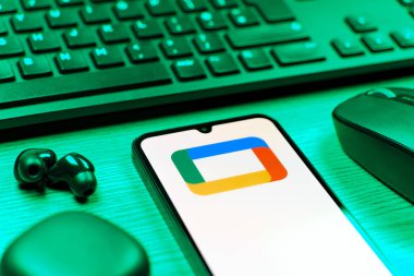 Prag, Çek Cumhuriyeti - 08 12 2025: Google TV logosunu gösteren klavyesi ve cep telefonu olan bir masanın yan görüntüsü. Google TV film, program ve uygulamalar için bir platformdur..