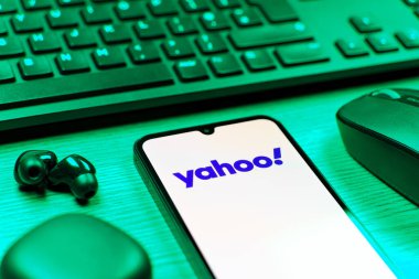 Prag, Çek Cumhuriyeti - 08 12 2025: Yahoo logosunu gösteren klavyesi ve cep telefonu olan bir masanın yan görüntüsü. Yahoo haber, e-posta ve internet hizmetleri için bir platformdur..