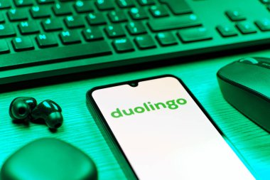 Prag, Çek Cumhuriyeti - 08 12 2025: Duolingo logosunu gösteren klavyesi ve cep telefonu olan bir masanın yan görüntüsü. Duolingo interaktif olarak dil öğrenmek için bir platformdur..