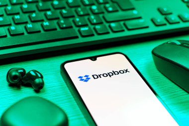 Prag, Çek Cumhuriyeti - 08 12 2025: Dropbox logosunu gösteren klavyesi ve cep telefonu olan bir masanın yan görüntüsü. Dropbox bulut depolama ve dosya paylaşımı için bir platformdur.