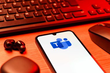 Prague, Czechia - 08 12 2025: A side view of a desk with a keyboard and a mobile phone displaying the Teams logo. Teams is a platform for team collaboration, meetings, and communication.