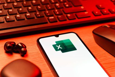 Prague, Czechia - 08 12 2025: A side view of a desk with a keyboard and a mobile phone displaying the Excel logo. Excel is a software for spreadsheets, data analysis, and calculations.
