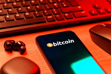 Prag, Çek Cumhuriyeti - 08 12 2025: Bitcoin logosunu gösteren klavyesi ve cep telefonu olan bir masanın yan görüntüsü. Bitcoin merkezi olmayan işlemler için dijital bir kripto para birimidir.