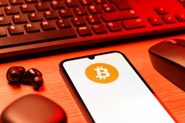 Prag, Çek Cumhuriyeti - 08 12 2025: Bitcoin logosunu gösteren klavyesi ve cep telefonu olan bir masanın yan görüntüsü. Bitcoin merkezi olmayan işlemler için dijital bir kripto para birimidir.