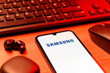 Prag, Çek Cumhuriyeti - 08 12 2025: Samsung logosunu gösteren klavyesi ve cep telefonu olan bir masanın yan görüntüsü. Samsung elektronik ve cihaz üreten bir teknoloji şirketi..