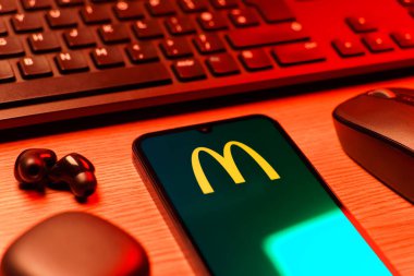 Prag, Çek Cumhuriyeti - 08 12 2025: McDonalds logosunu gösteren klavyesi ve cep telefonu olan bir masanın yan görüntüsü. McDonalds hamburger, patates kızartması ve daha fazlası sunan bir fast-food zinciri..
