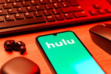 Prag, Çek Cumhuriyeti - 08 12 2025: Hulu logosunu gösteren klavyesi ve cep telefonu olan bir masanın yan görüntüsü. Hulu TV şovları, filmler ve canlı TV için bir yayın platformu..