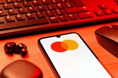 Prag, Çek Cumhuriyeti - 08 12 2025: Mastercard logosunu gösteren klavyesi ve cep telefonu olan bir masanın yan görüntüsü. Mastercard ödeme kartları ve hizmetler sağlayan bir finans şirketidir..