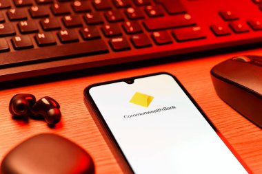 Prag, Çek Cumhuriyeti - 08 12 2025: Commonwealth Bank logosunu gösteren klavyesi ve cep telefonu olan bir masanın yan görüntüsü. Commonwealth Bank, Avustralya 'da finansal hizmetler sağlayan bir bankadır..