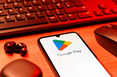 Prag, Çek Cumhuriyeti - 08 12 2025: Google Play logosunu gösteren klavyesi ve cep telefonu olan bir masanın yan görüntüsü. Google Play uygulamaları, oyunları ve dijital içeriği indirmek için bir platformdur.