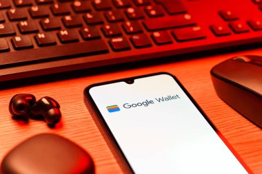 Prag, Çek Cumhuriyeti - 08 12 2025: Google Cüzdan logosunu gösteren klavyesi ve cep telefonu olan bir masanın yan görüntüsü. Google Cüzdanı dijital ödeme yöntemlerini depolamak ve kullanmak için bir platformdur.