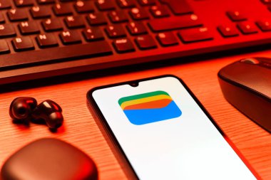 Prag, Çek Cumhuriyeti - 08 12 2025: Google Cüzdan logosunu gösteren klavyesi ve cep telefonu olan bir masanın yan görüntüsü. Google Cüzdanı dijital ödeme yöntemlerini depolamak ve kullanmak için bir platformdur.