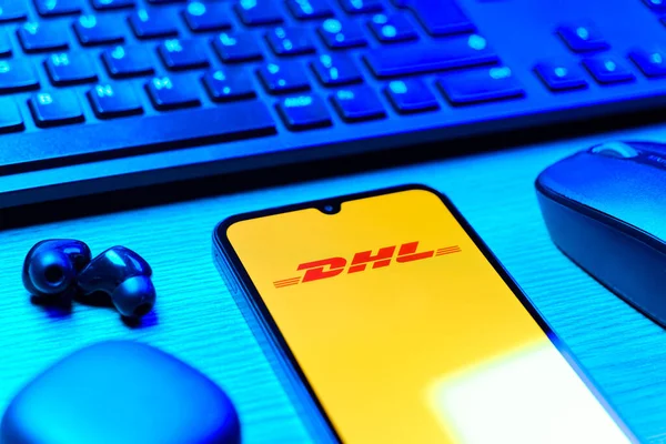 Prag, Çek Cumhuriyeti - 08 12 2025: DHL logosunu gösteren klavyesi ve cep telefonu olan bir masanın yan görüntüsü. DHL uluslararası nakliye hizmeti sunan bir lojistik şirketidir..